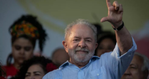 Presença de Lula no Rio atrai multidão. Foto de Lula fazendo o sinal de L com a mão e sorrindo.