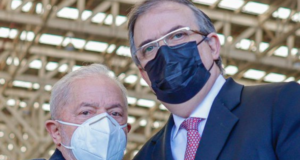 Lula chega ao México e agradece secretário de López Obrador. Os dois estão abraçados um na lateral do outro e utilizando máscara.