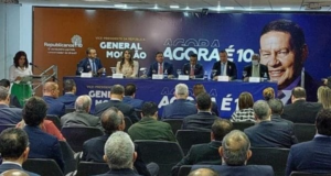 Militares fazem pouco caso de filiação de Mourão ao Republicanos. Foto do evento de filiação de Mourão, pessoas em um auditório com uma mesa e um banner com a imagem do vice-presidente.