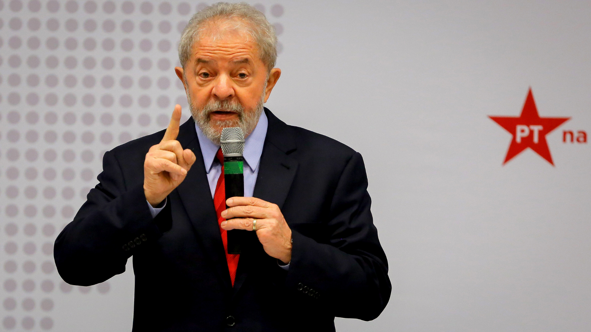 Lula é o candidato predileto dos evangélicos, diz pesquisa BTG. Foto do presidente falando ao microfone, com terno preto, apontando o dedo indicador direito para cima.