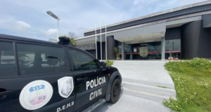 Polícia prende acusados de manter empresário em cativeiro na cidade de Manaus. Foto da sede da polícia junto com um carro ao lado.