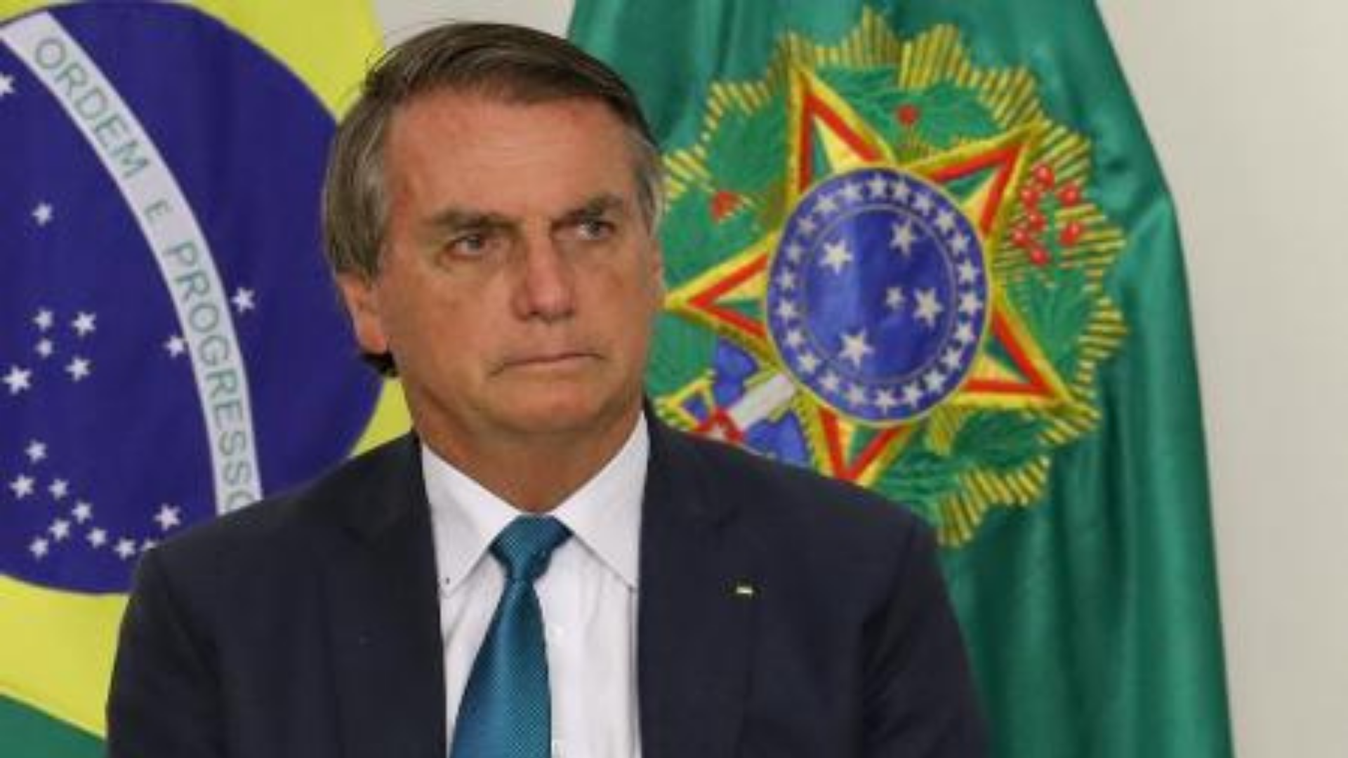 Bolsonaro tem expressão séria, desmotivante, usa terno preto e olhar fixo., ele pode não comemorar o golpe de 64