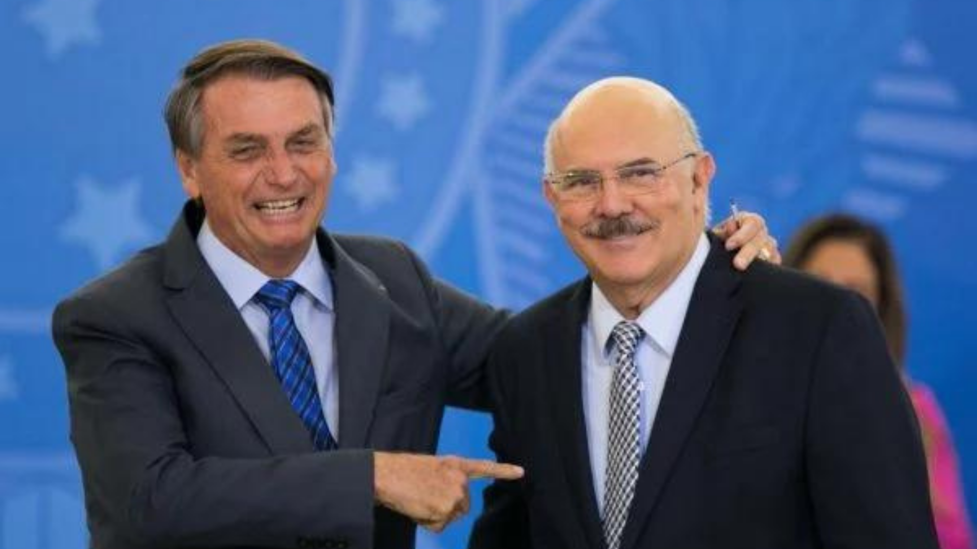 Em live, Bolsonaro diz que bota "a cara no fogo" por Milton Ribeiro. Foto do presidente Bolsonaro apontando o dedo e sorrindo para Milton Ribeiro.