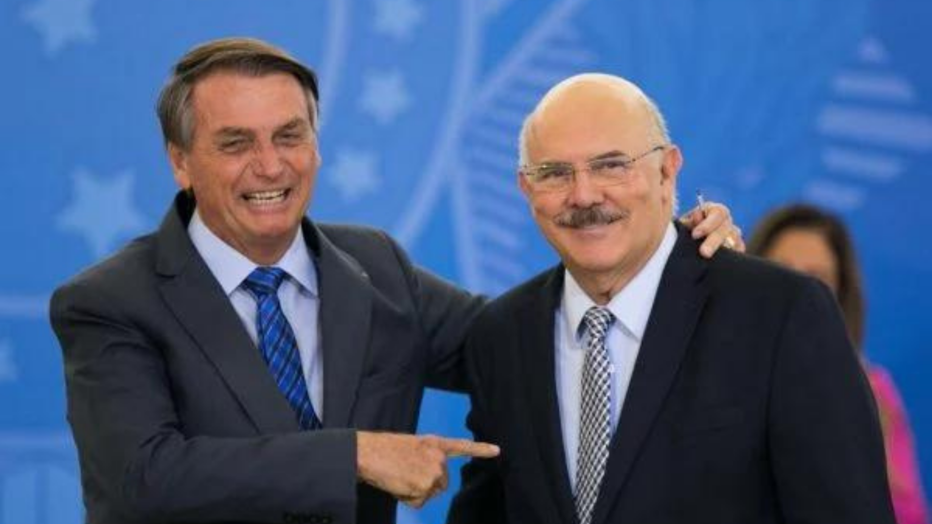 Bolsonaro sorrindo e apontando para Milton Ribeiro