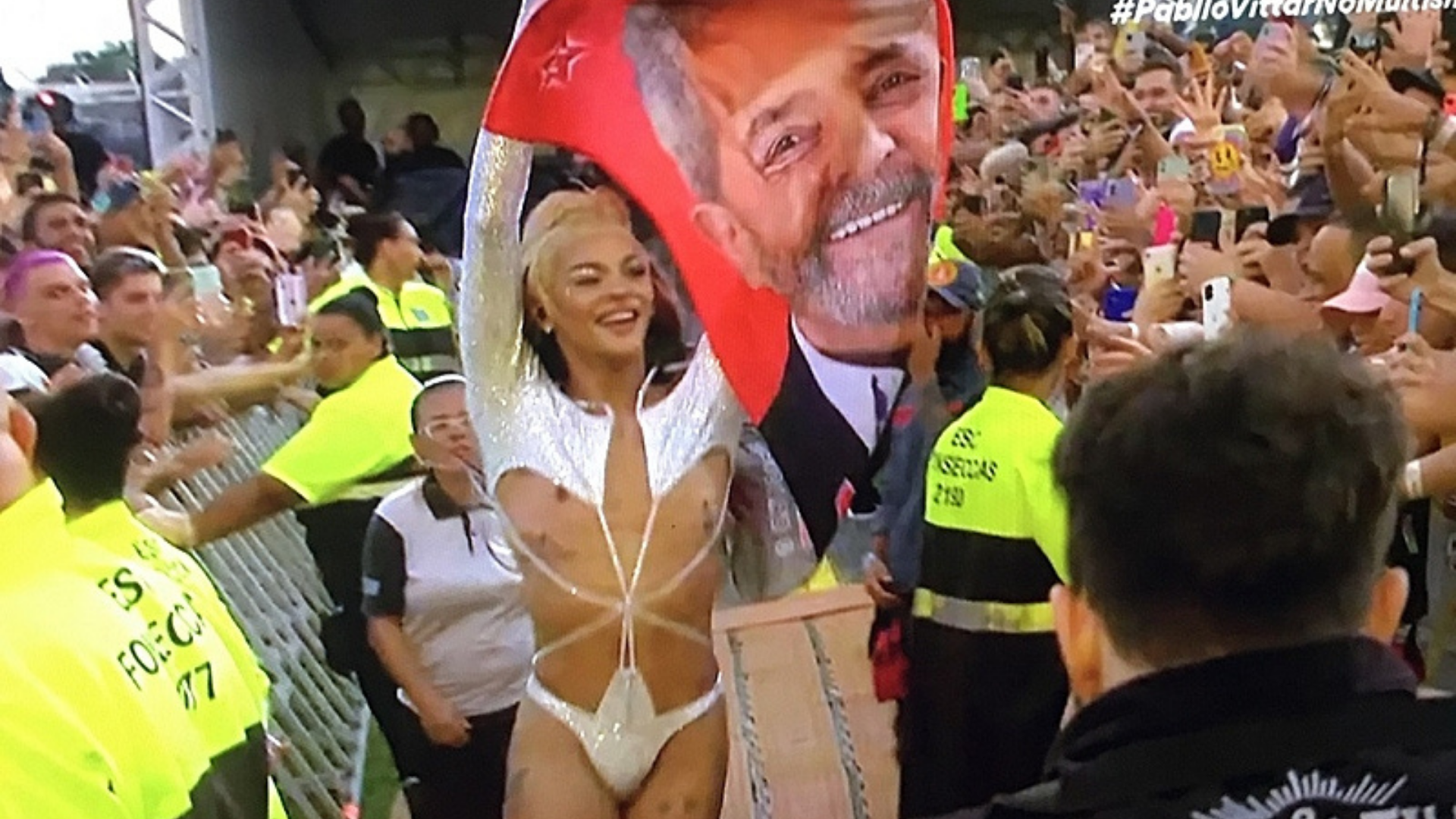 Pabllo Vittar exibe toalha com rosto de Lula no Lollapalooza. Foto de Pabllo durante o Lolla levantando bandeira de Lula.