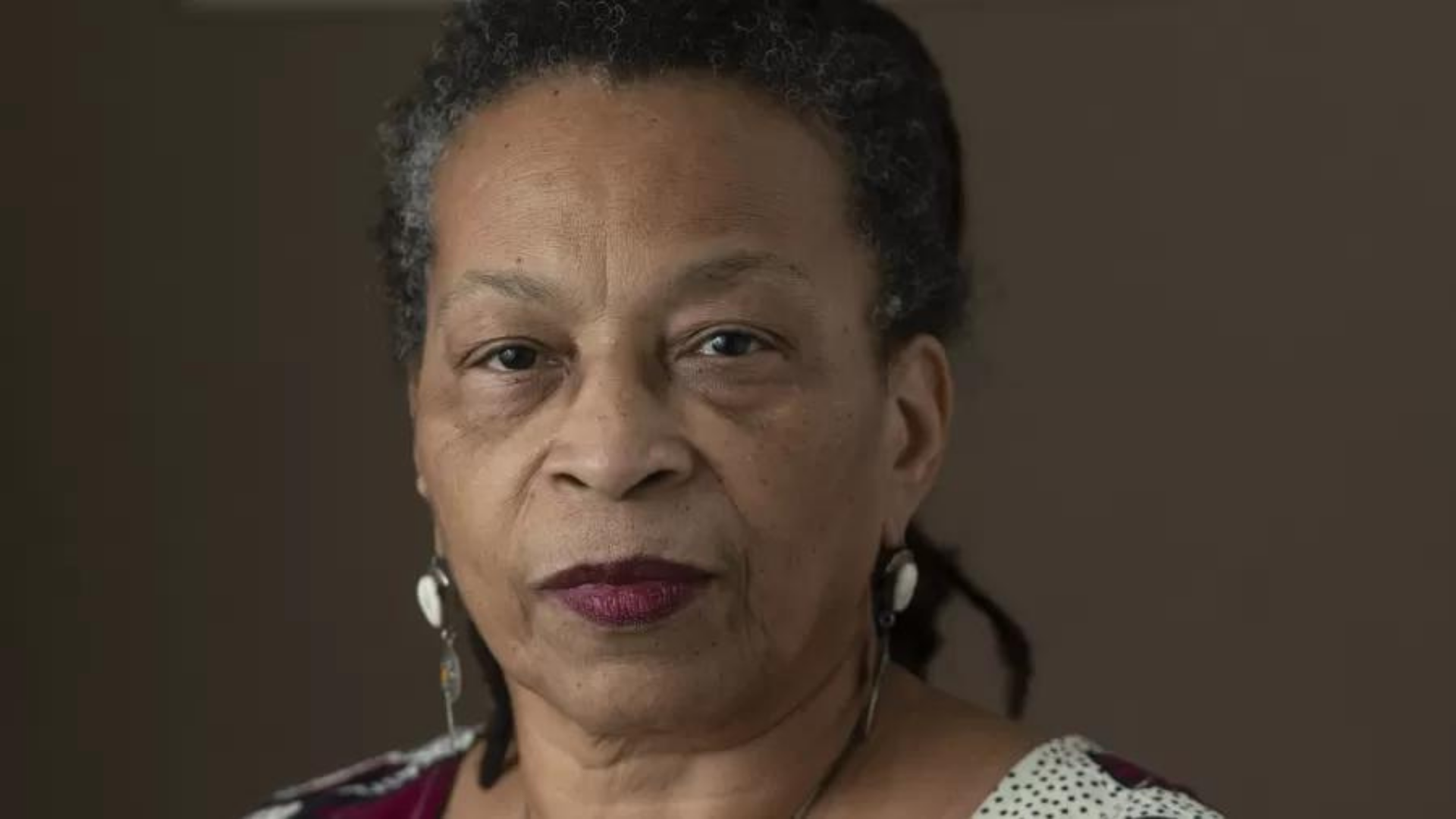 Brasileira irá denunciar racismo no Brasil em evento da ONU. Foto de Lucia Xavier com expressão séria, ela tem cabelo grisalho e pele negra. 