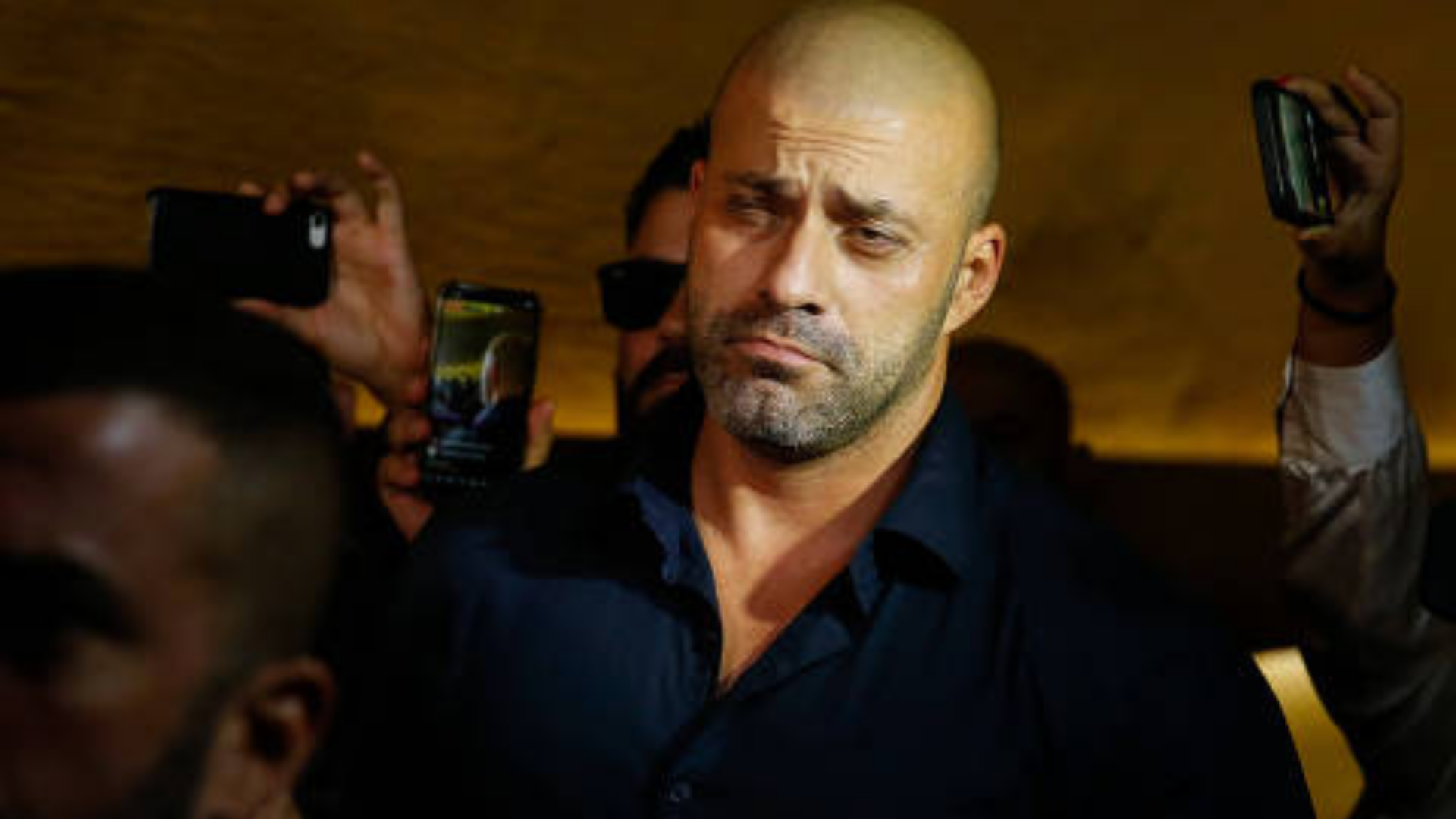 Daniel Silveira não aguenta pressão e deve colocar tornozeleira. Foto do deputado com olhar sério e olhos semi abertos.