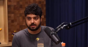 Monark e Ferréz migram para plataforma concorrente do YouTube. Foto de Monark falando ao microfone. Ele tem cabelos pretos e barba preta.