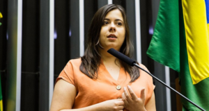Câmara aprova pedido de Sâmia Bomfim contra o Mamãe Falei. Ela usa um vestido bege e fala no plenário da Câmara