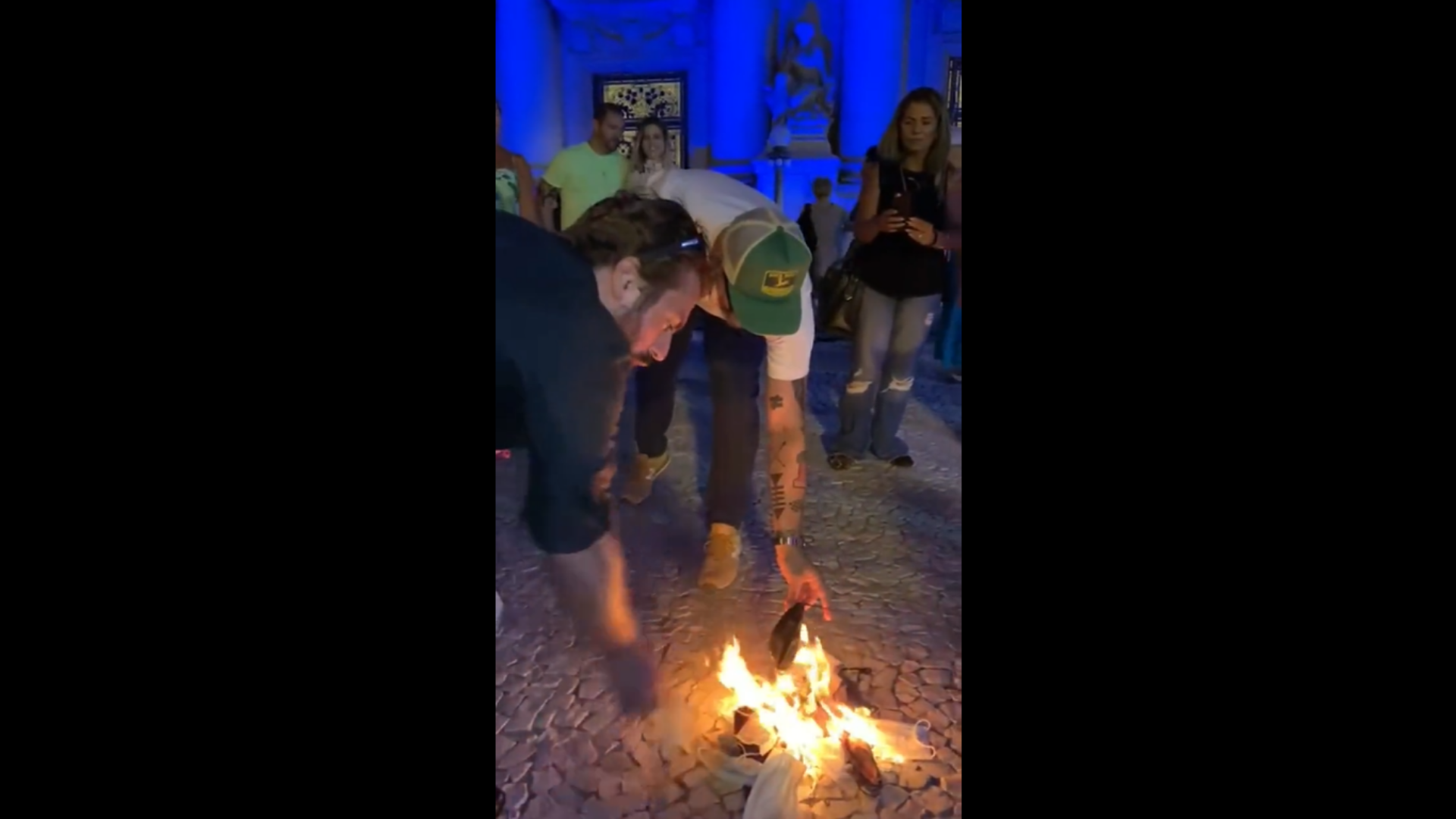 Negacionistas queimam máscaras e desafiam Eduardo Leite. Foto de manifestantes colocando máscaras no fogo