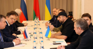 Terceira rodada de negociações entre Rússia e Ucrânia. Foto de representantes dos dois países em uma mesa.