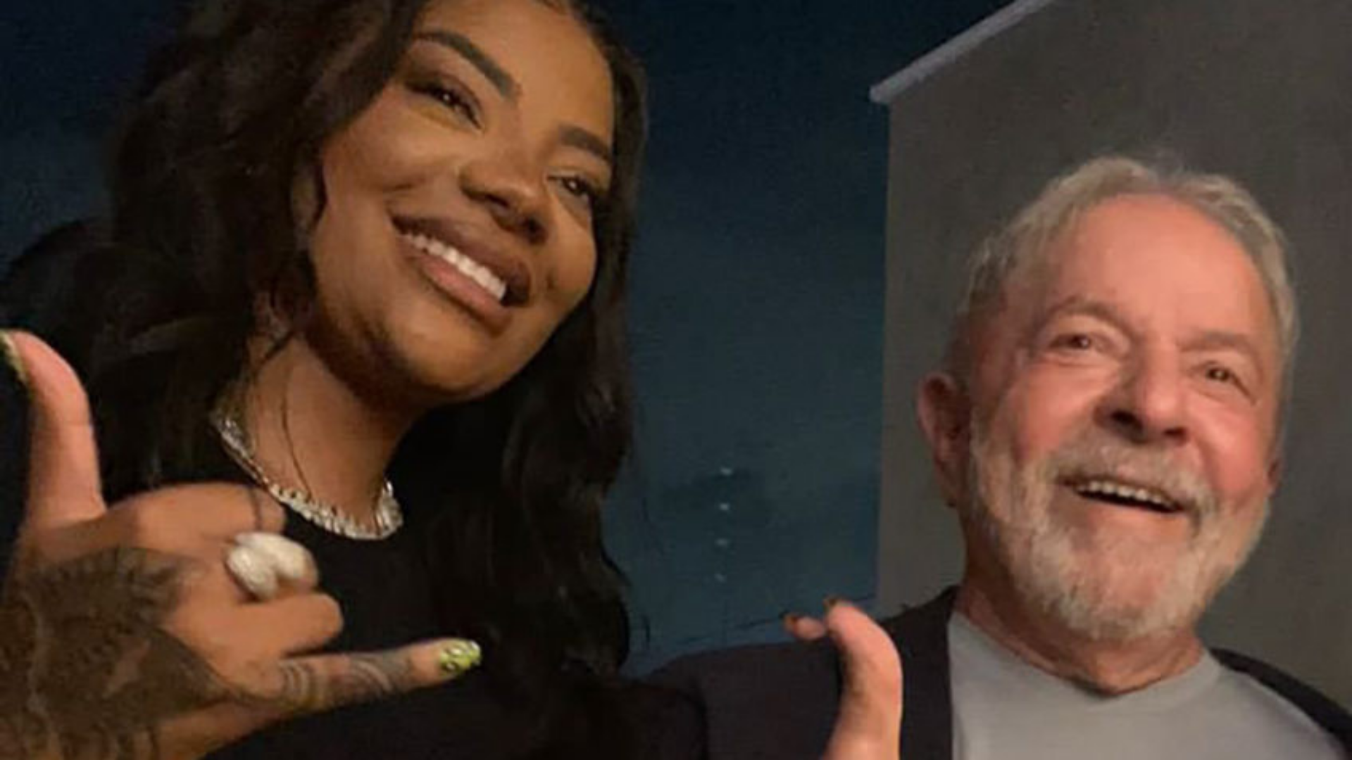 Ludmilla se encontra com o ex-presidente Lula. Eles estão sorrindo abraçados lateralmente.