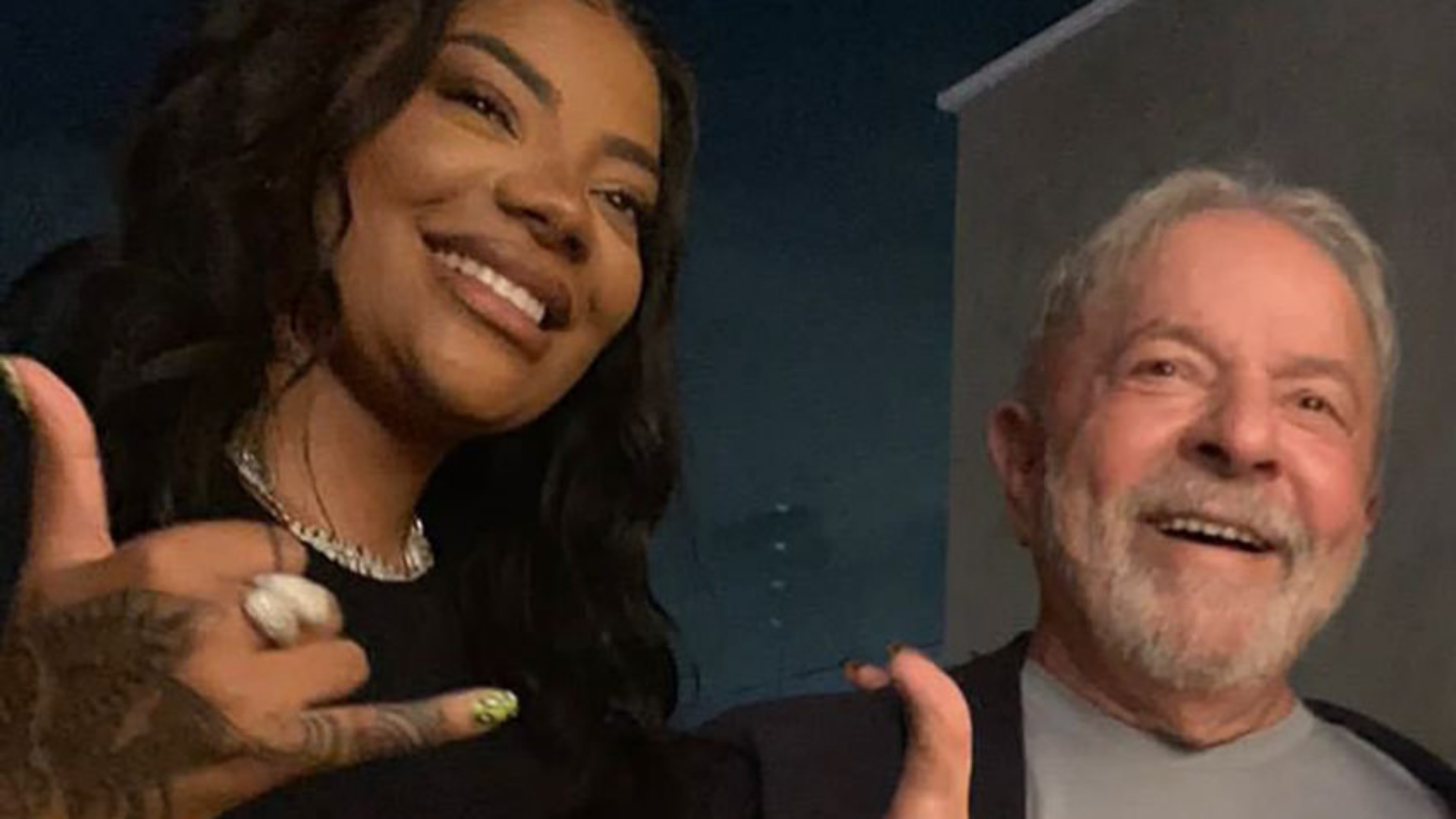 Ludmilla se encontra com o ex-presidente Lula. Eles estão sorrindo abraçados lateralmente. 