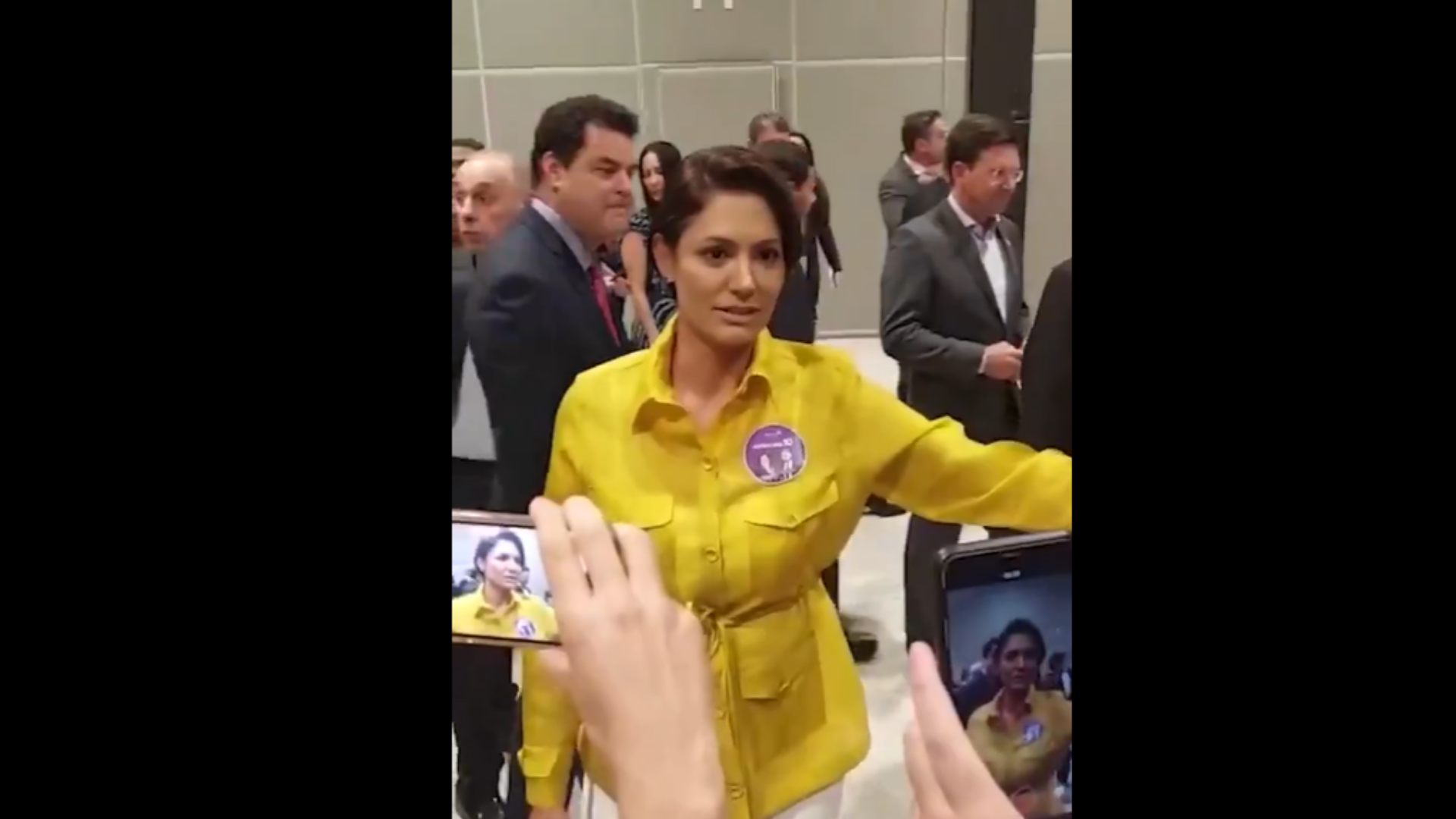 Primeira-dama não fala de propinas e defende Milton Ribeiro: "Confio nele". Foto de Michelle com blusa amarela e olhar sereno.