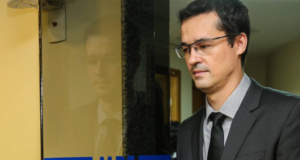 Deputado detona Deltan Dallagnol. O ex-procurador tem um olhar triste e cabisbaixo, ele usa terno preto e está mirando o chão.