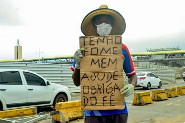 Imagem de um homem com um cartaz dizendo que tem fome; Brasil foi mal no ranking de país mais feliz do mundo