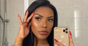 Foto da modelo Carolina Lekker com o celular na mão, em frente ao espelho. A foto mostra apenas seu rosto.
