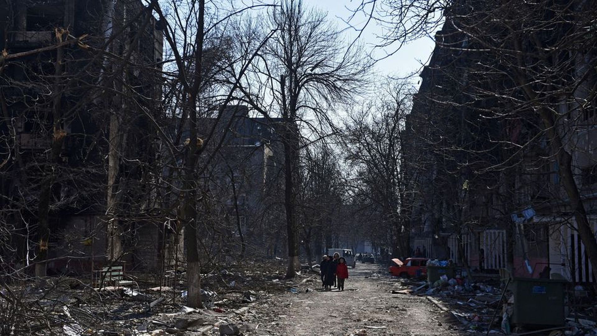 Moradores locais caminham perto de edifícios residenciais que foram danificados durante o conflito Ucrânia-Rússia na cidade portuária sitiada de Mariupol, Ucrânia, em 18 de março de 2022