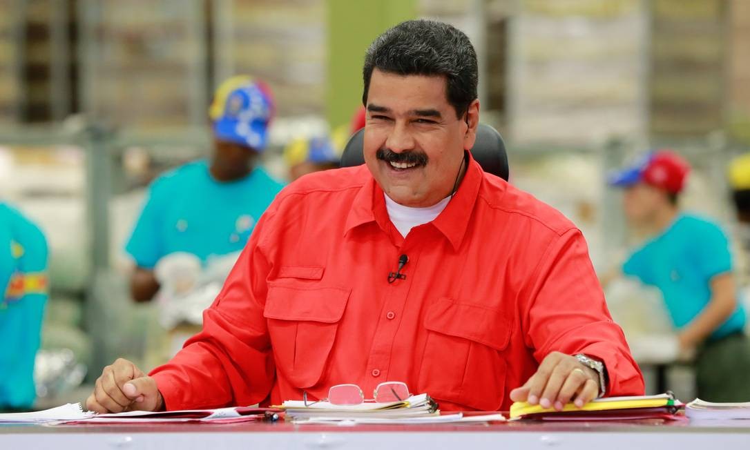 Nicolás Maduro, presidente da Venezuela, sorrindo durante discurso. Ele veste uma camisa vermelha.
