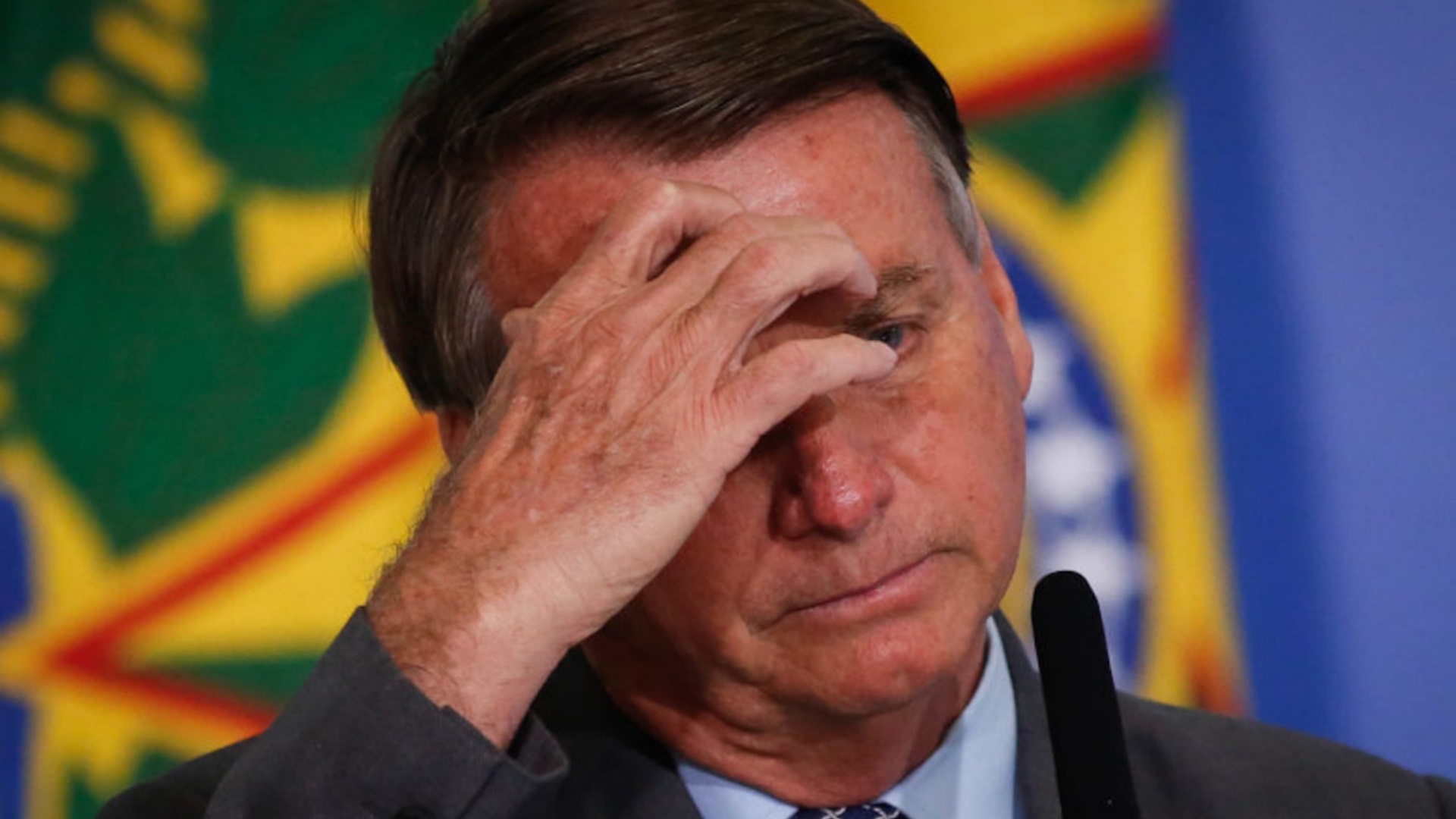 O presidente Jair Bolsonaro com a mão no rosto, se lamentando.