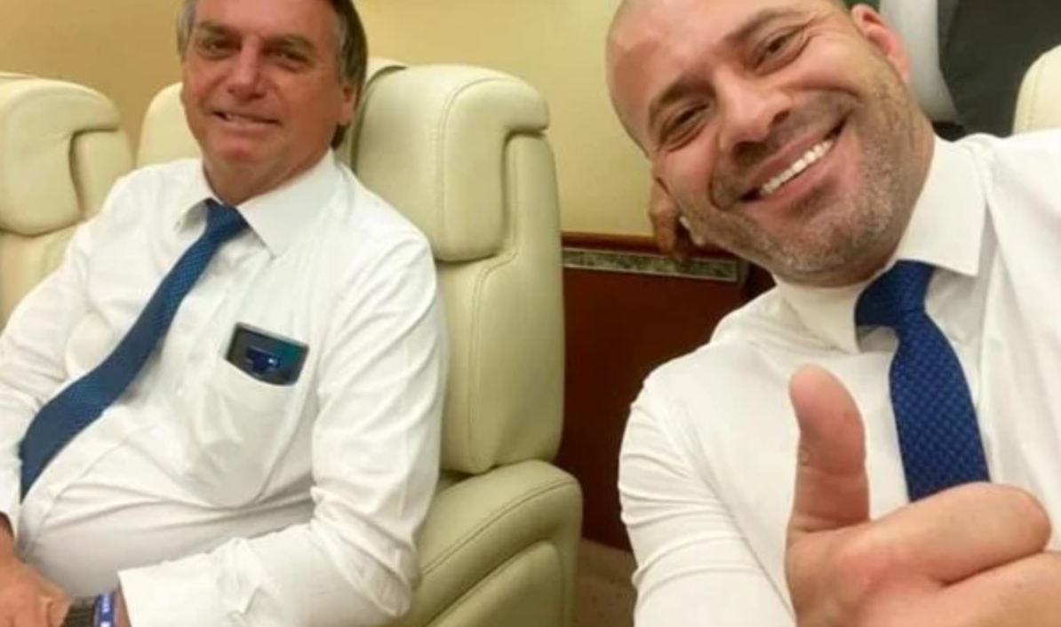 Bolsonaro e Daniel Silveira sentados em um avião e sorrindo para a foto.