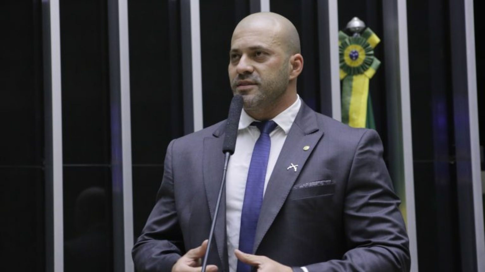 Foto de Daniel Silveira usando terno e falando no plenário da Câmara. 