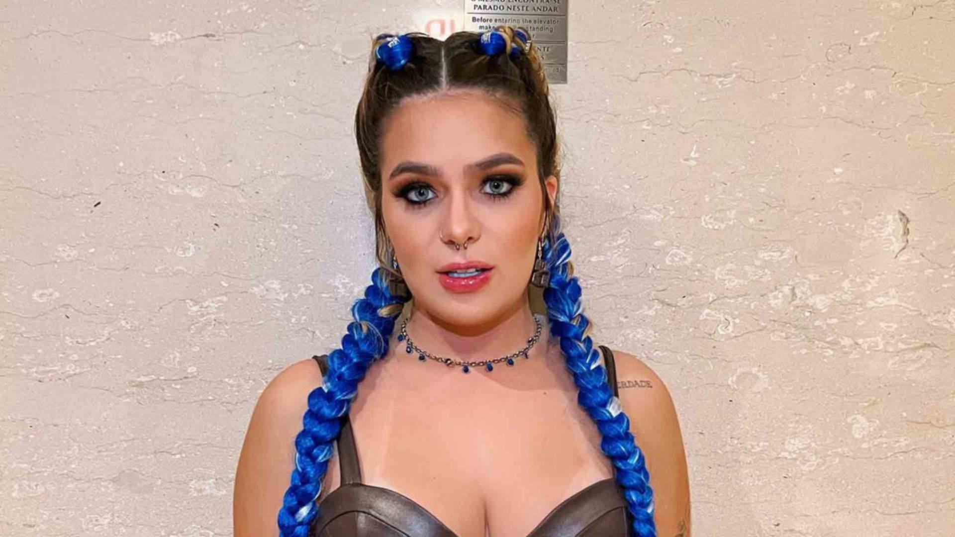 Viih Tube aparece fantasiada com tranças no cabelo, pintado com a cor azul, e olhar sério.