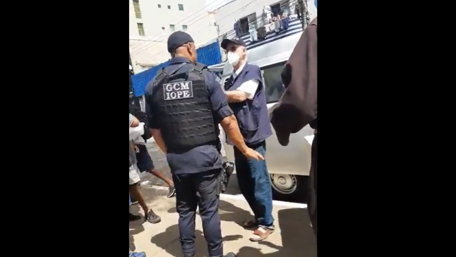 GCM tenta impedir padre Julio Lancellotti de distribuir quentinhas em SP. Foto de Julio Lancelotti discutindo com um agente na rua. 