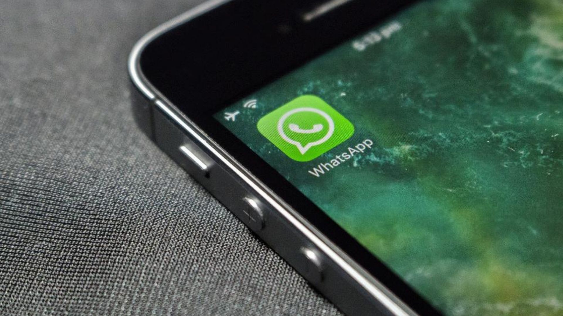 Foto de um celular com o ícone do aplicativo WhatsApp sendo mostrado na tela.