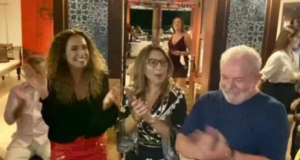 Lula dança ao lado de Daniela Mercury. O ex-presidente aparece em foto com uma camisa azul, ao lado de Daniela Mercury e Janja, que estão sorrindo e dançando no terraço da casa.