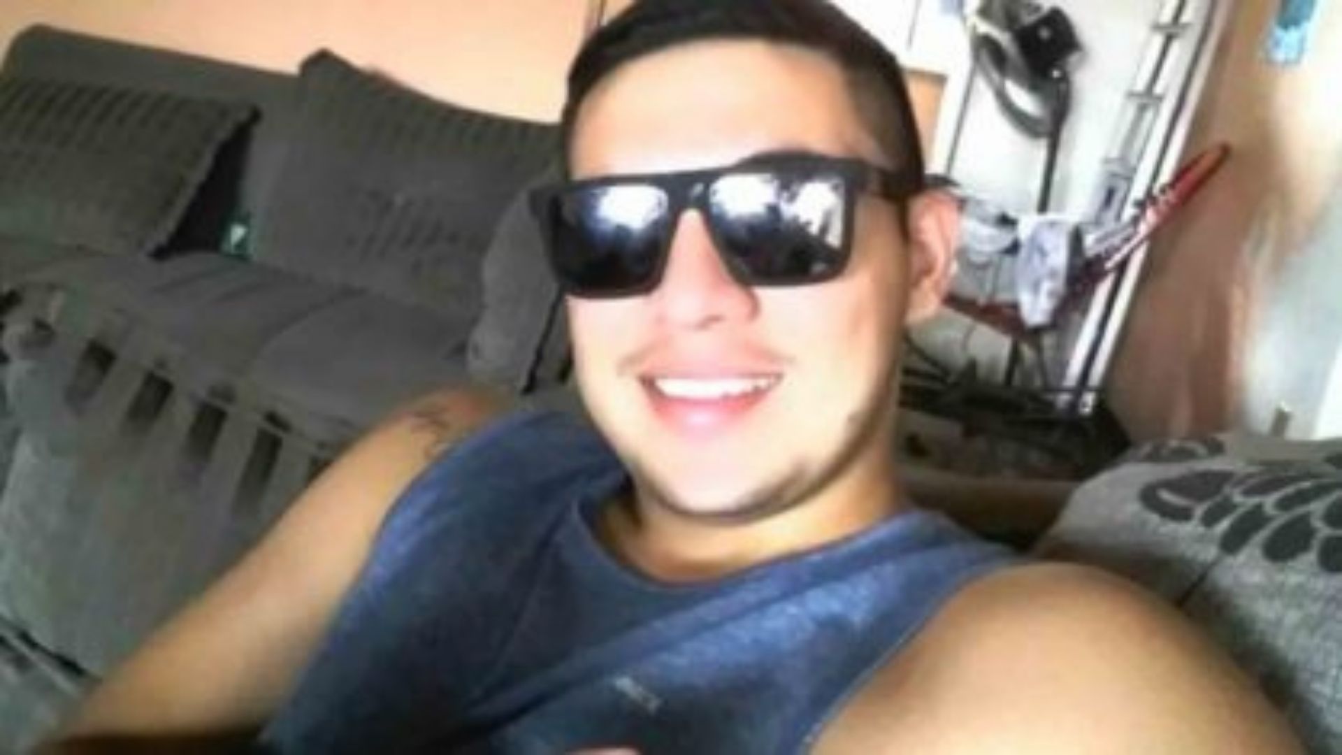 Foto do marinheiro sorrindo com um óculos de sol e cabelo preto.