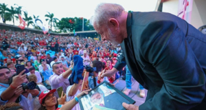 “Já ouço Lula presidente”, diz o ator Rodrigo Lombardi. Foto de Lula com a cabeça abaixada falando com uma apoiadora.