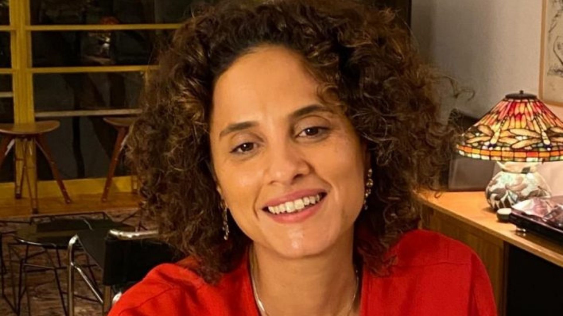 Foto de Inês dos Santos com cabelos cacheados na cor castanho, sorri à foto. Ela tem pele negra.