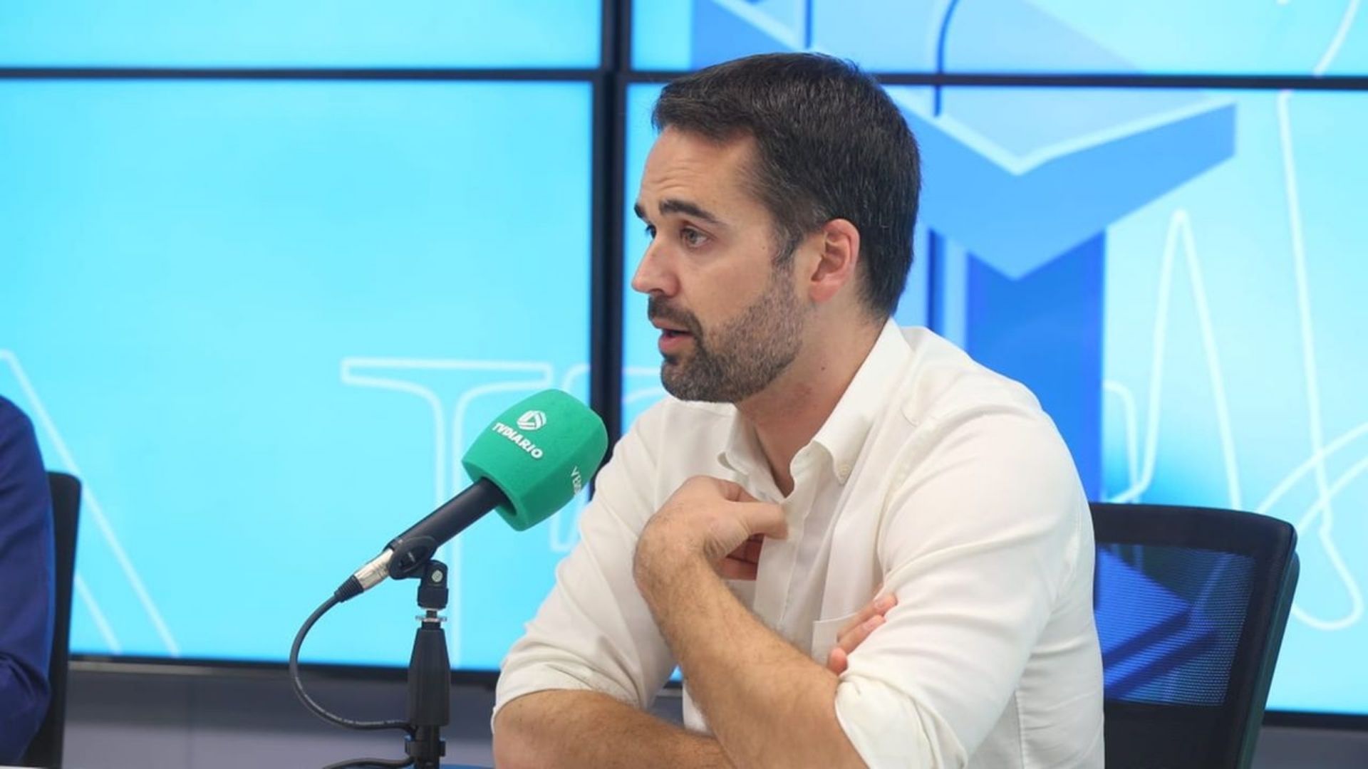 Foto de Eduardo Leite flando ao microfone em uma entrevista de rádio.