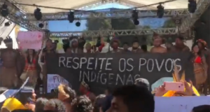 Foto de indígeas Pataxó em protesto com uma frase em cartaz escrita "Respeito os Povos Indígenas"
