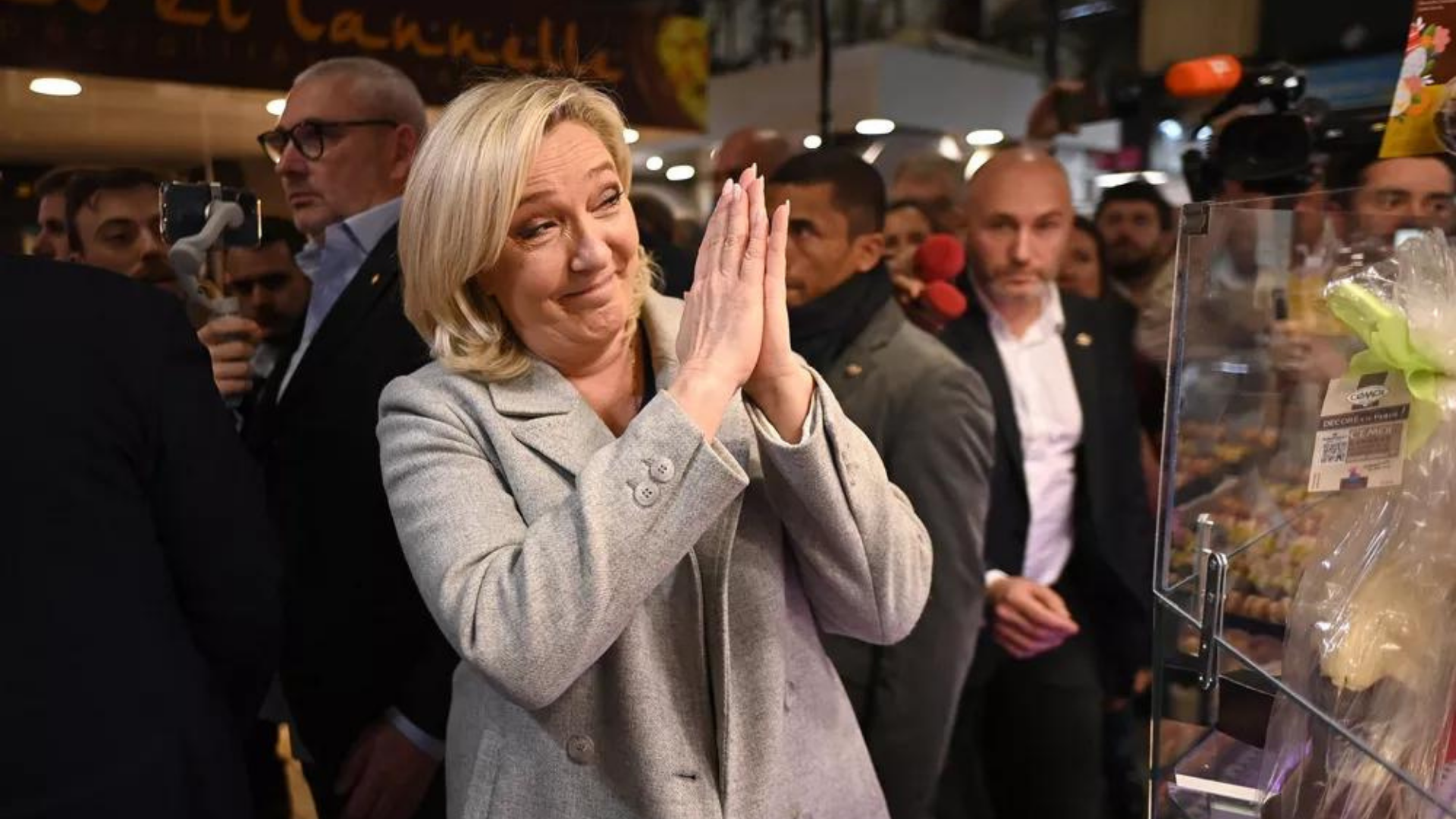 Marine Le Pen sorri para alguém e tem as mãos no formato de oração, demonstrando esperança. 