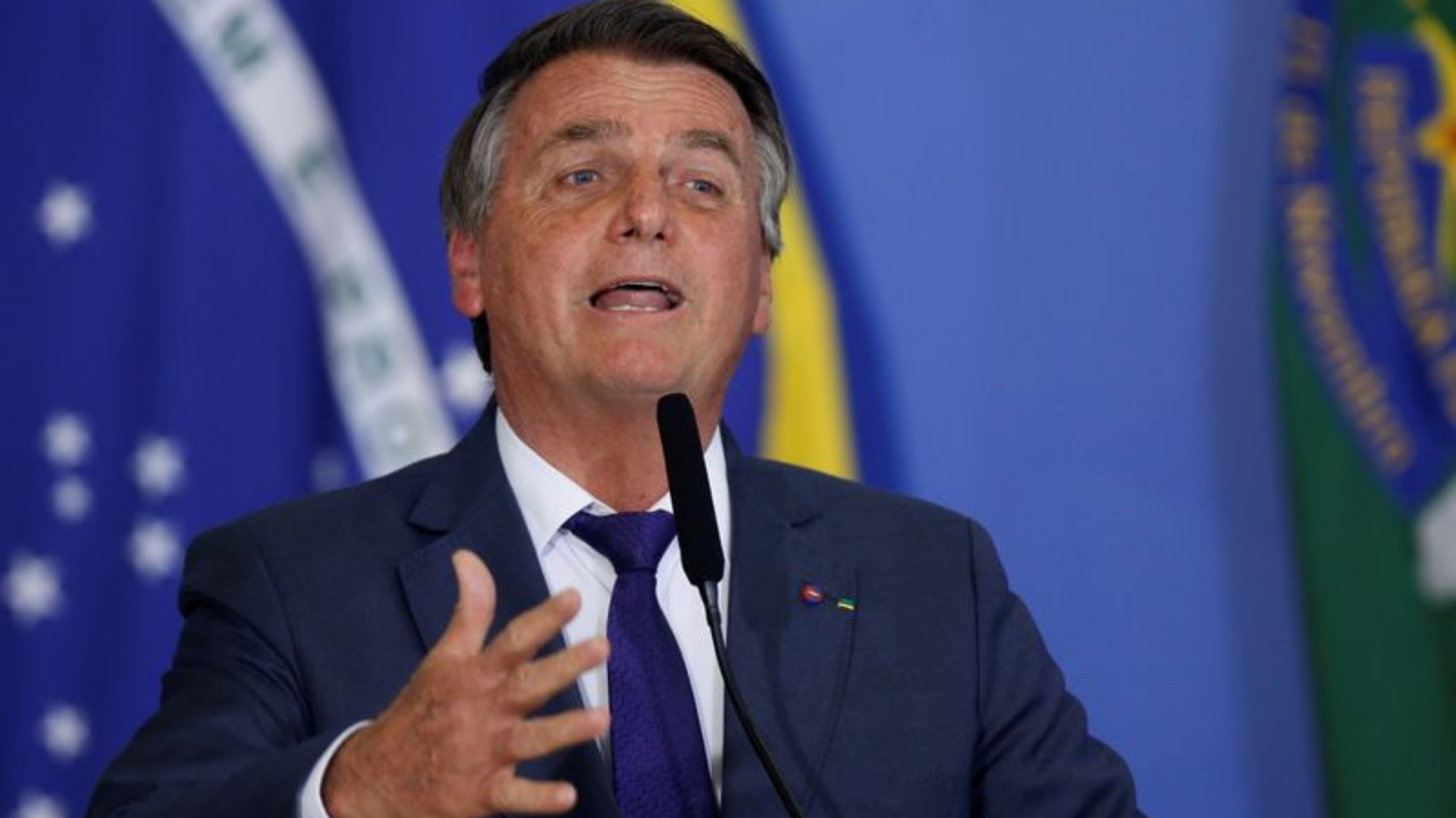 Foto de Bolsonaro com expressão exaltada falando ao microfone.