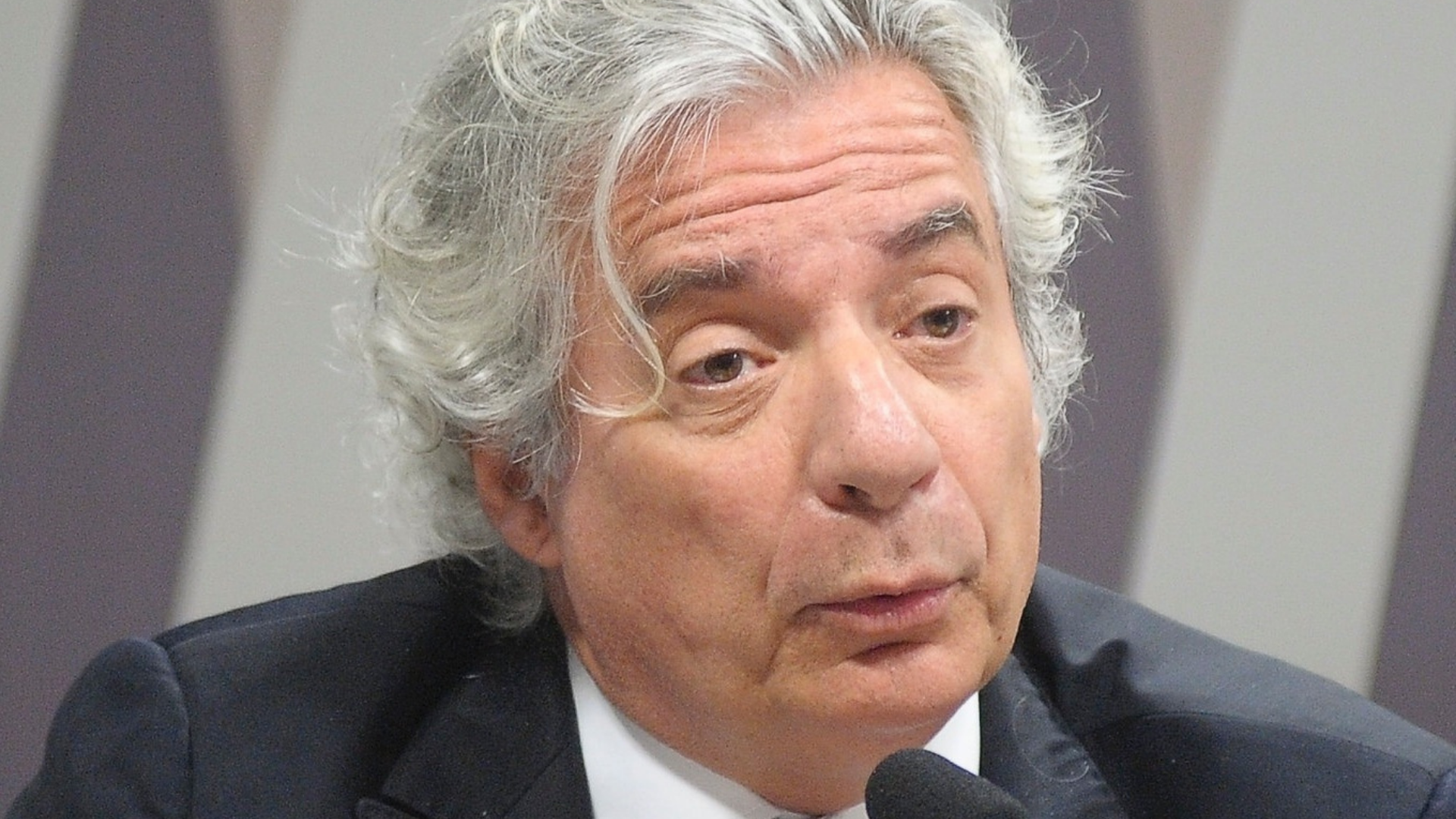 MP e TCU entram na Justiça para que Adriano Pires não assuma a presidência da Petrobras. Foto do rosto de Adriano Pires, com pelo branca, cabelo branco e e falando em um microfone de mesa.