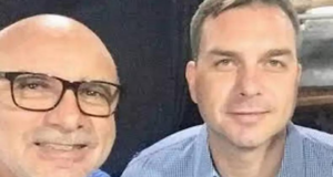 Foto de Fabrício Queiroz ao lado de Flávio Bolsonar, os dois estão sorrindo.