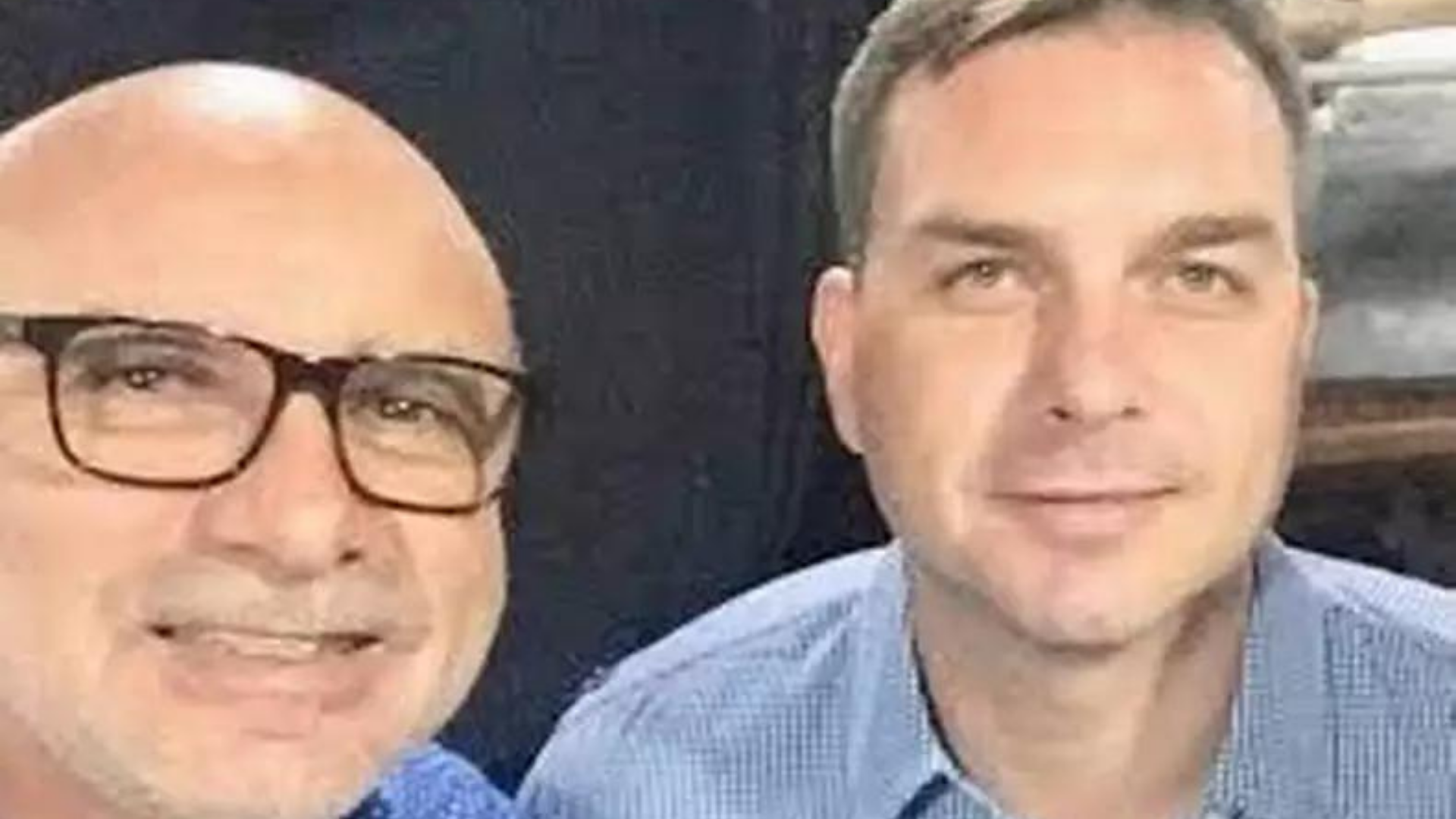 Foto de Fabrício Queiroz ao lado de Flávio Bolsonar, os dois estão sorrindo.