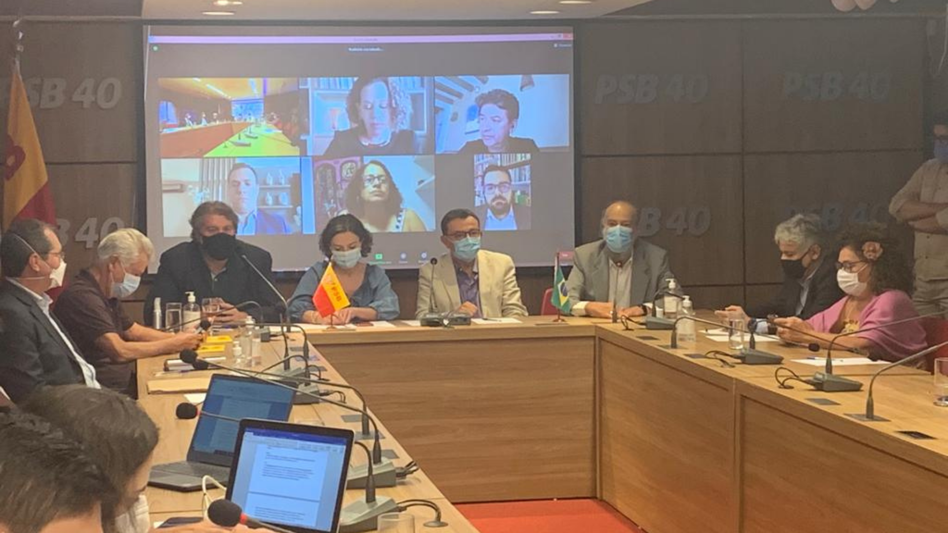 Foto de mesa de reunião com integrantes do PCdoB, PV e PT.