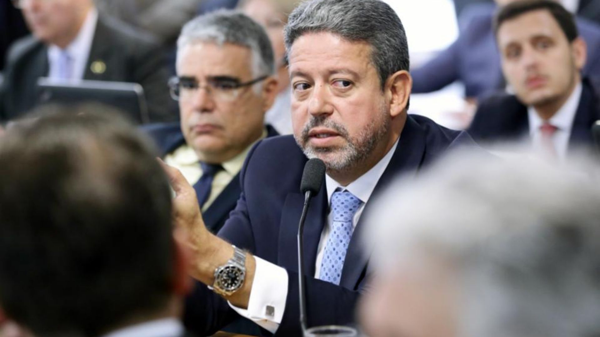 Arthur Lira tem cabelos grisalhos e barba grisalha. Ele tem olhar de preocupação e pele branca.