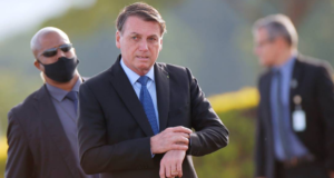 Bolsonaro usa terno preto e camisa branca e tem expressão desconcertada enquanto caminha.