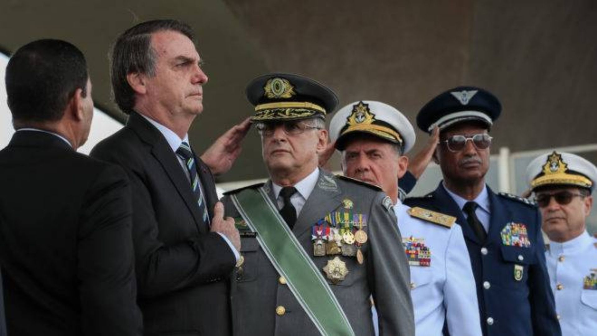 Bolsonaro aparece em um evento com representantes das forças armadas prestando continência a ele.