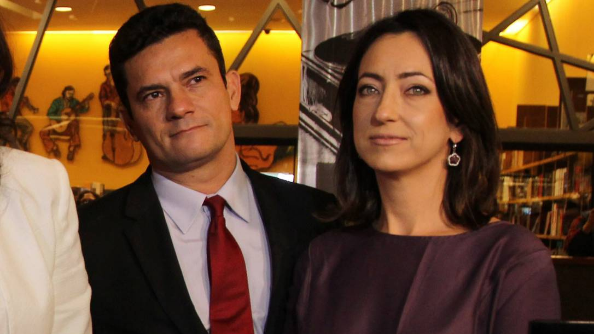 Foto de Moro e Rosangela com rousas de gala um ao lado do outro durante um evento.