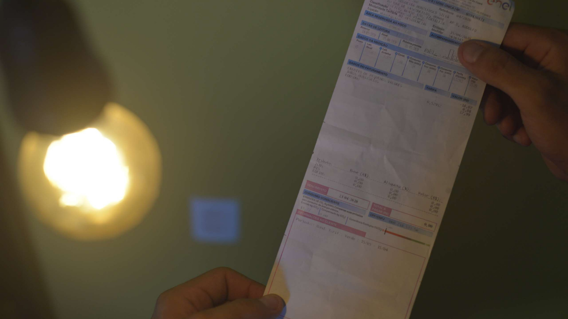 Taxa extra na conta de luz acaba e preços devem cair. Foto de um papel de uma conta de luz embaixo de uma lâmpada.