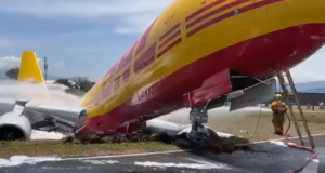 Avião cargueiro roda na pista e fica com fuselagem destruída. Foto do avião, nas cores amarela e vermelha, com a estrutura quebrada.