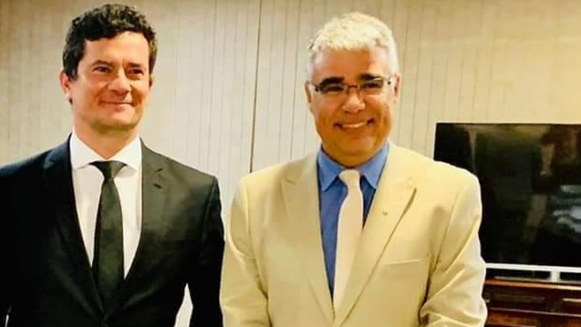 Senador Girão bancou viagem de Moro à Alemanha. Foto de Moro, com terno preto e sorrindo, ao lado de Girão, com terno branco, óculos de grau e sorrindo. 