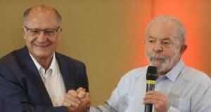 Lula e alckmin aparecem em aperto de mãos em um evento.