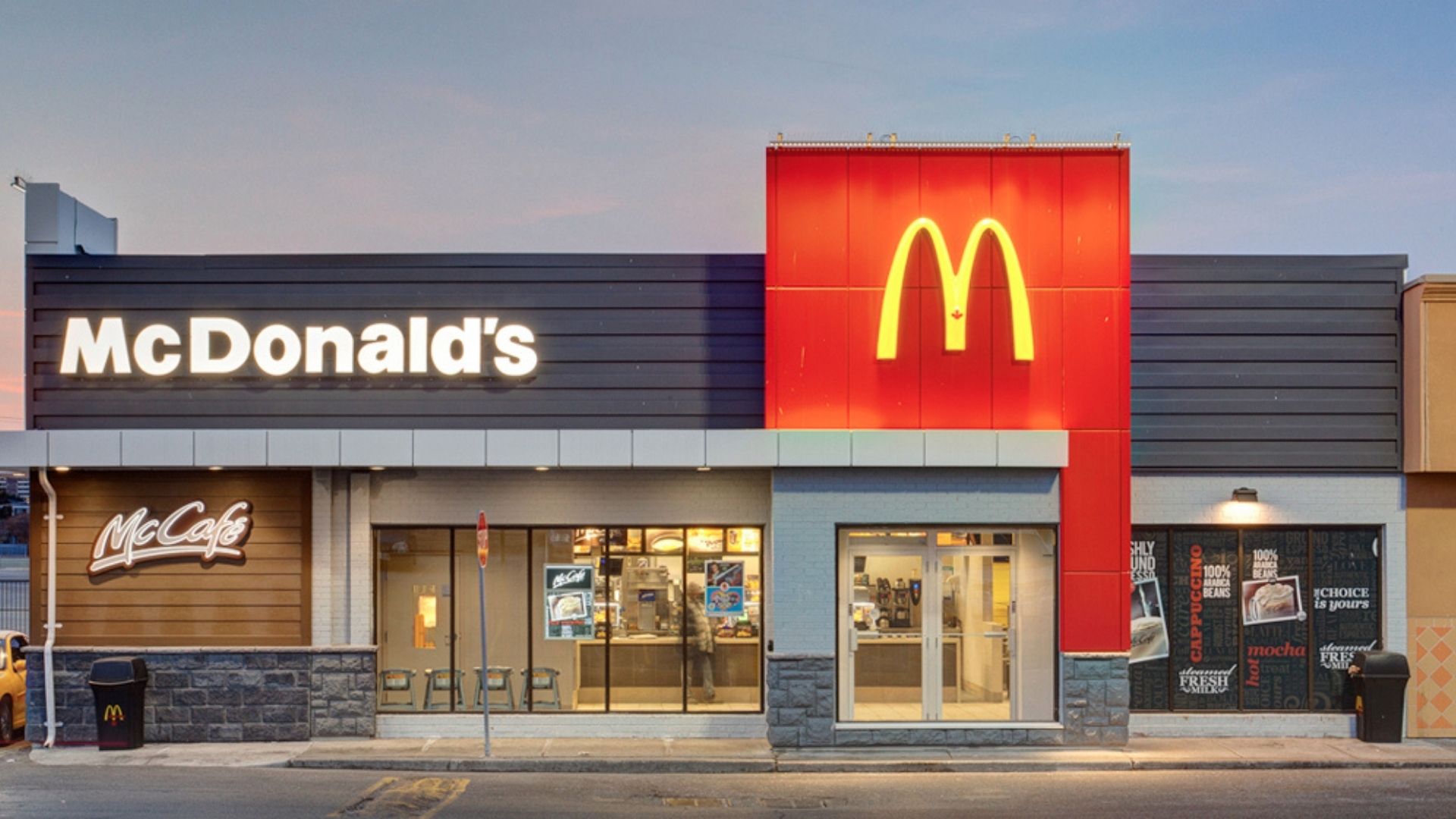Foto de uma fachada de loja do Mc Donald's. M amarelo com uma das paredes na cor vermelha, em um prédio simples feito de tijolos.
